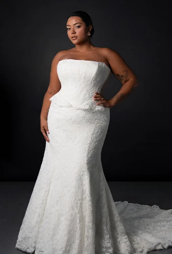 Plus size bride wearing lace strapless fit-and-flare wedding dress with peplum waist