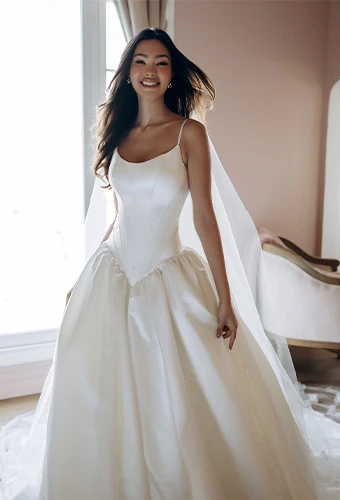 Bride wearing simple drop waist satin ballgown wedding dress with scoop neckline and spaghetti straps