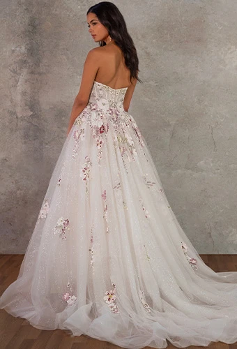Bride showing the back of a glitter tulle A-line wedding dress with an embroidered lace trail and sweeping train.