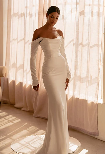 Bride posed in a sculpted strapless silk gown beside a golden-lit window, Martina Liana ML1997.
