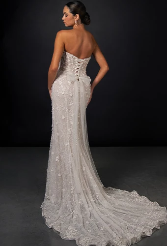 Bride showing off the back of her fit-and-flare wedding gown with lace-up back and classic fabric buttons that flow into a train