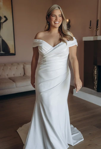 Bride walking and smiling in an off the shoulder gown, Stella York SY8330.