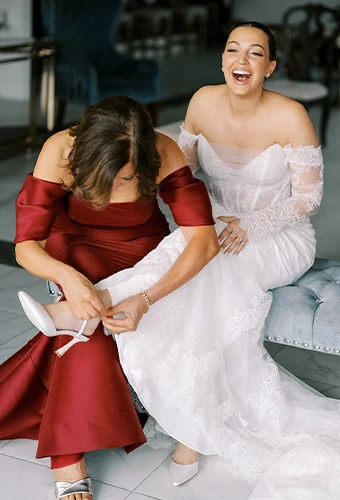 Real bride Alexa and a bridesmaid laughing together in a bridal suite