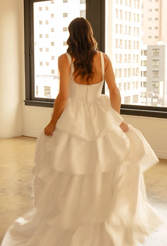Bride wearing satin a line wedding dress with straps, square back and overskirt