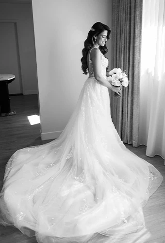 Real bride Olivia in a white strapless wedding dress with flowing train, holding white bouquet in black and white