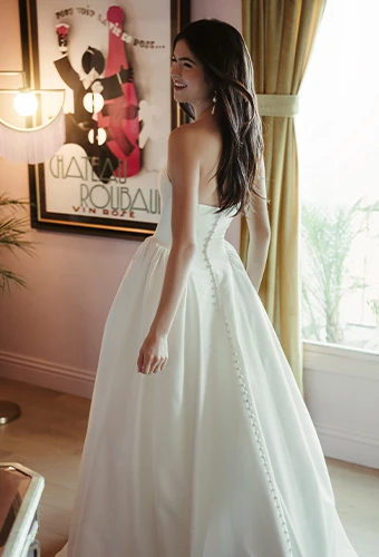 Bride wearing strapless ballgown wedding dress with straight across neckline and fabric covered buttons