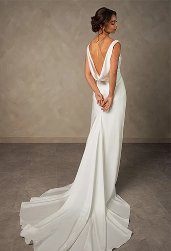 Bride wearing simple column wedding dress with open back and cowl detail