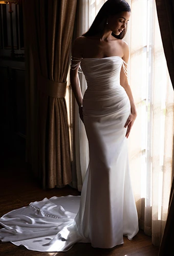 Bride wearing strapless silk column wedding dress with off-shoulder pearl strands, Essense of Australia D4607