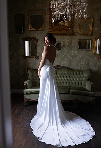Bride showing off back of column sheath gown with open back and bow train, Essense of Australia D4614
