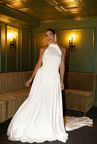 Bride wearing high-neck silk wedding dress with drop waist and pleated train, All Who Wander ramone
