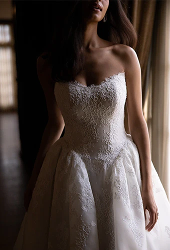 Bride wearing strapless ballgown wedding dress with allover lace and basque waist
