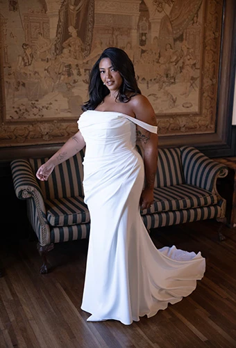 Plus size bride wearing asymmetric ruched crepe wedding gown with off-shoulder straps, Essense of Australia D4563+