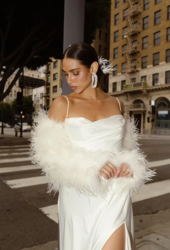 Bride poses in simple silk wedding dress with fur accessories and statement earrings, All Who Wander rianna