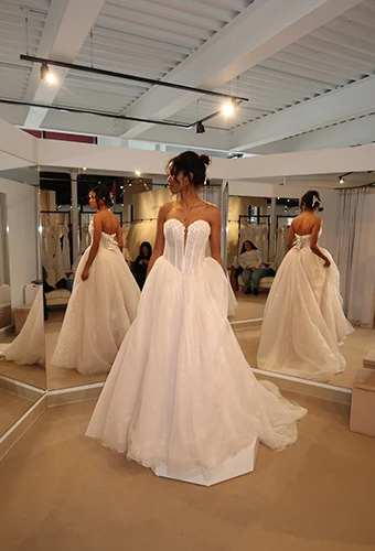 Bride-to-be trying on a strapless wedding dress with plunging neckline and full tulle skirt at a bridal appointment