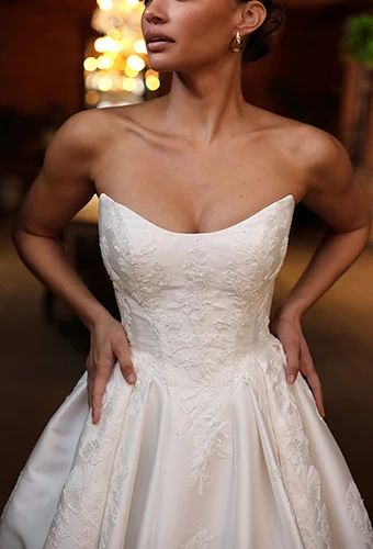 Close up of bride wearing strapless wedding ballgown with cat eye neckline and floral embroidery, Essense of Australia D4265