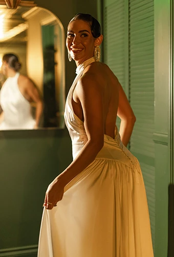 Bride smiles in charmeuse wedding gown with high neckline, open back and drop waist, All Who Wander ramone