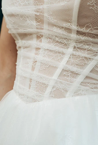 Close up of sheer ruched bodice with exposed boning and floral lace details, Stella York SY8087