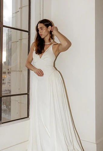 Bride posing in silk A-line wedding dress with V-neckline and sweeping panels, All Who Wander gisele