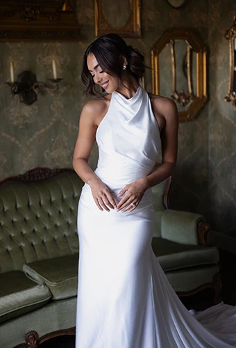 Bride smiling in simple satin wedding dress with high neck and long flowy train, Essense of Australia D4614