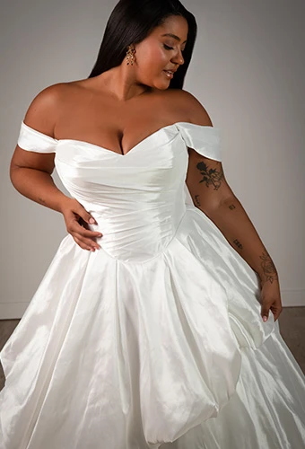 Plus size bride wearing ballgown wedding dress with off the shoulder straps