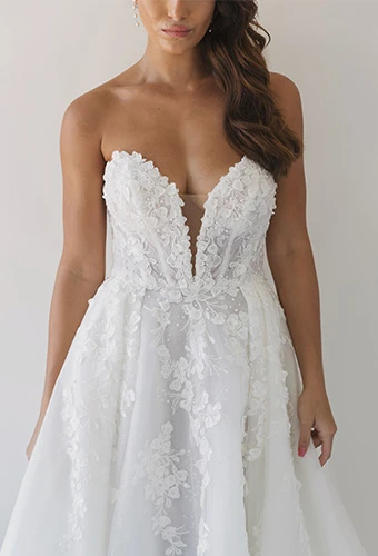 Bride wearing strapless wedding gown with floral lace and illusion plunge