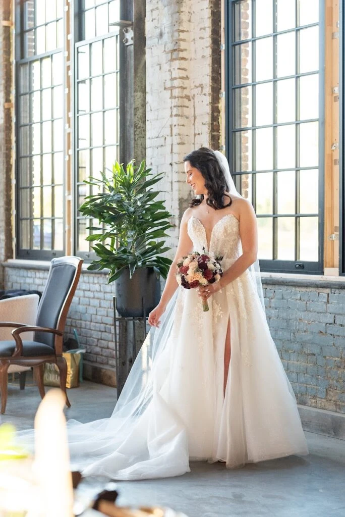 Real bride Melissa posing in her wedding gown with a flower bouquet