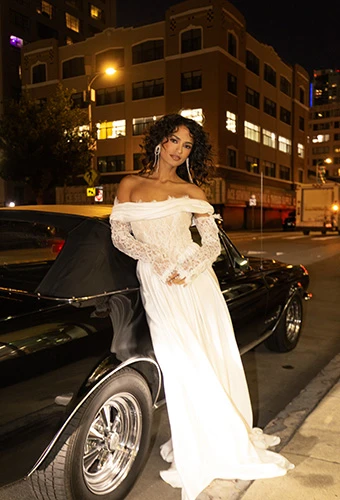 Bride wearing a boho A-line wedding gown with off-the-shoulder long sleeves and lace bodice, All Who Wander joplin