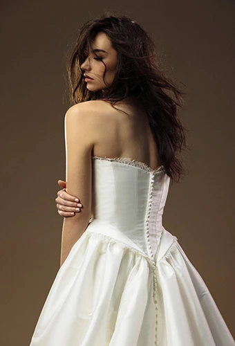Bride wearing basque waist wedding dress with lace detailing and streamlined button closure, All Who Wander lynlee