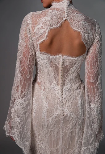 Bride wearing lace wedding gown with long sleeves and fabric covered buttons
