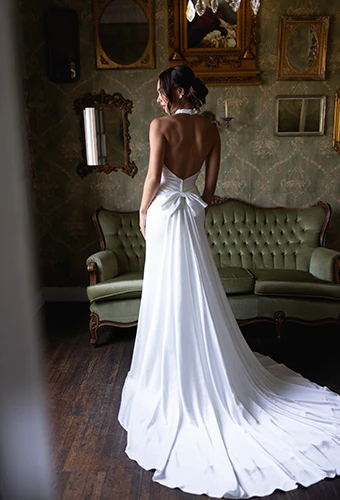 Bride wearing column wedding dress with halter neck, open back and detachable bow train, Essense of Australia D4614