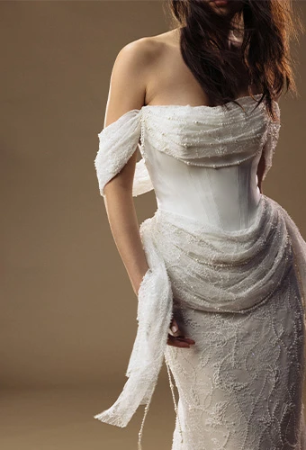 Bride wearing column wedding dress with off the shoulder straps and beaded lace draping