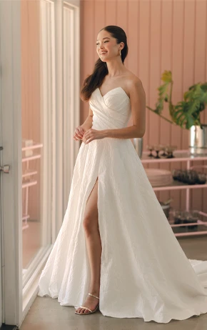 Stella York SY8191 A-Line wedding gown with a strapless sweetheart neckline, lace detailing on the bodice, and a full tulle skirt. Photographed outdoors with greenery and a light pink wall in the background.