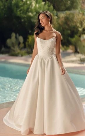 Ballgown wedding dress by Stella York, style SY8239. Includes a strapless sweetheart neckline, floral lace bodice, and a full tulle skirt. Outdoor setting with green grass and a pink brick wall.