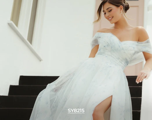 Stella York bridal gown SY8215, a light and airy off-the-shoulder A-line dress with a subtle blue floral pattern, high leg slit, and full tulle skirt, as the bride descends stairs.
