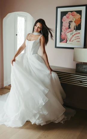 Bride in Stella York Style SY8222 standing in front of a dresser flaring out the bottom of the gown.
