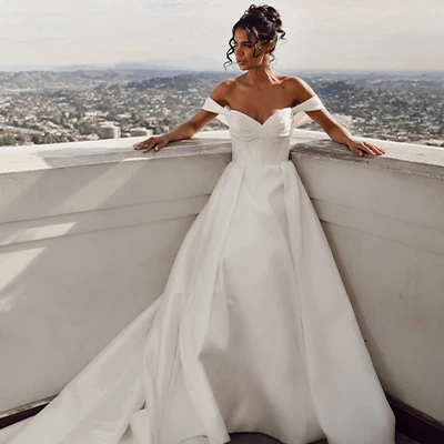 Bride wearing off-the-shoulder silk ballgown wedding dress with train